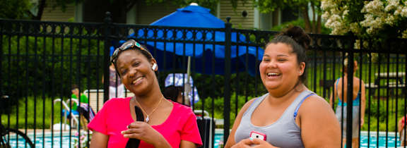 Two women standing by a pool.