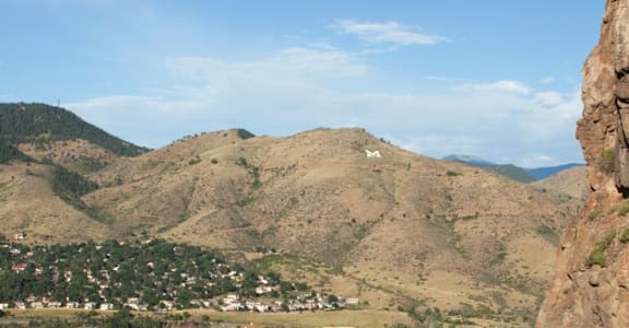 A town nestled in a valley with a large rock formation in the foreground.
