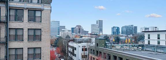 A wooden rooftop deck with a blue table and chairs overlooking a city skyline.