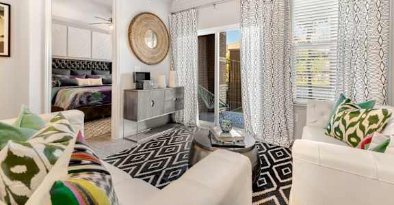 A living room with a white couch and a black and white patterned rug.