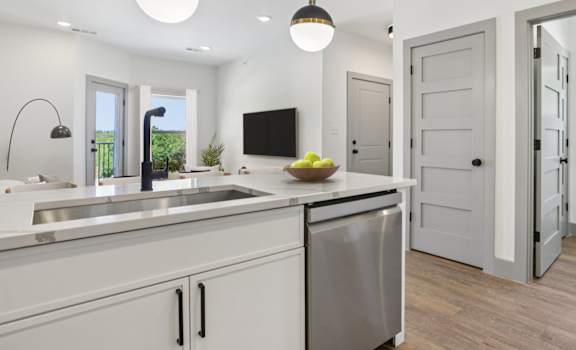 A modern kitchen with white cabinets and a wooden floor.
