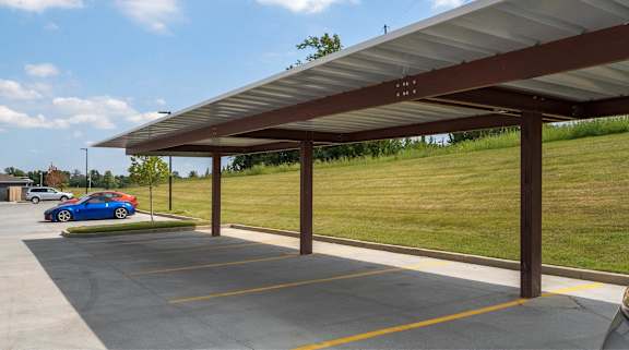 A blue car is parked in a parking lot under a covered structure.