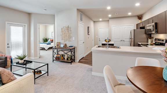 A modern living room with a white sofa, a glass coffee table, and a dining area with a white table and chairs.