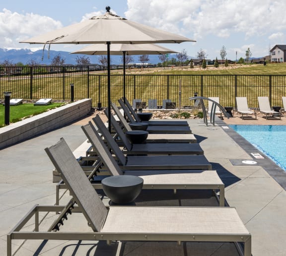 a row of lounge chairs and an umbrella next to a pool at Upland Flats, Colorado, 80922