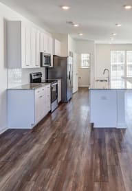 an empty living room with a ceiling fan and a kitchen