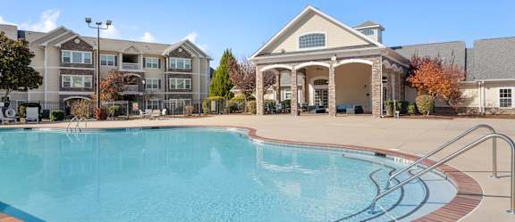 A large room with a blue couch and a chandelier. at Stone Gate Apartments, North Carolina