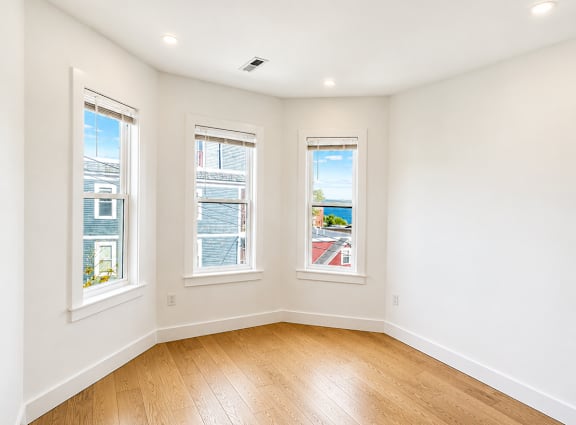 A room with wooden floors and two windows.