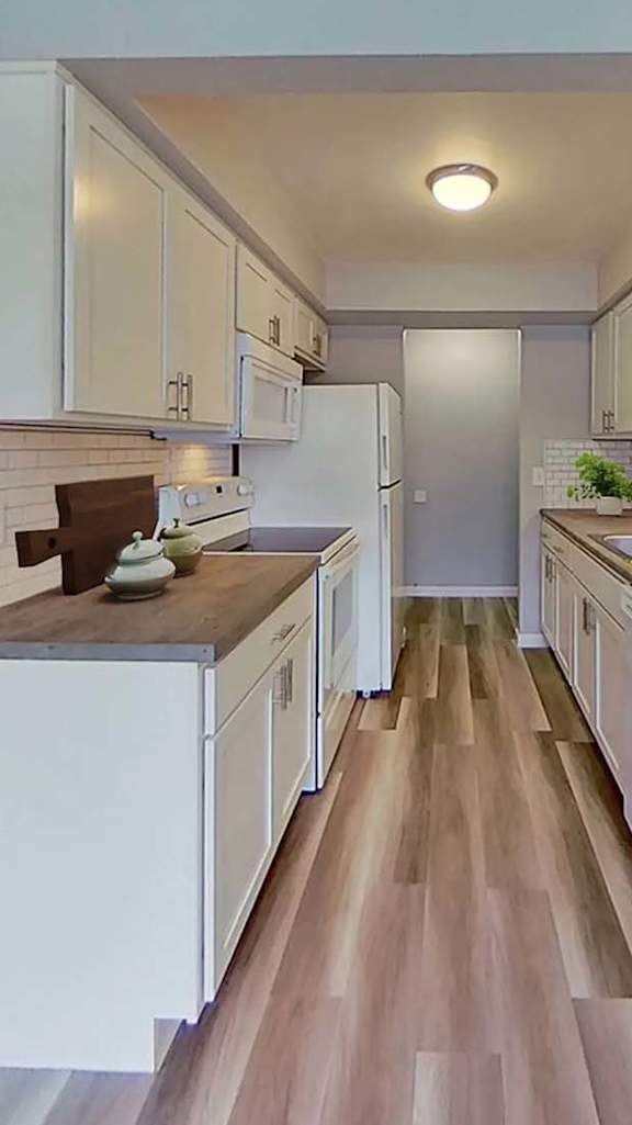 A kitchen with white cabinets and a wooden floor.