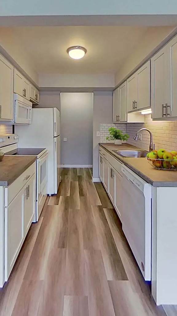 A kitchen with white cabinets and a wooden floor.