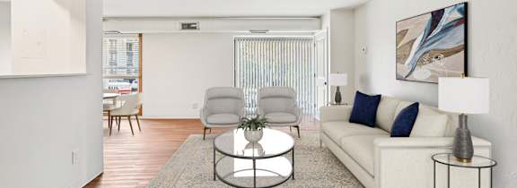 A living room with a white couch, a coffee table, and a painting on the wall.