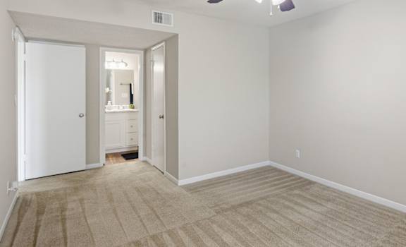 A room with a ceiling fan and carpeted floor.
