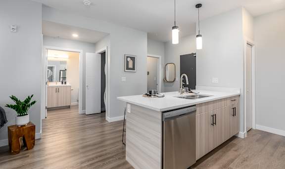 A modern kitchen with a white countertop and stainless steel appliances.