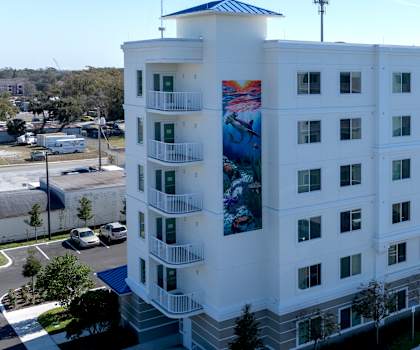 A large white hotel with a blue and red mural on the side.