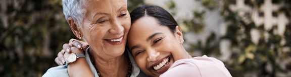 An older woman hugging a younger woman in a garden.