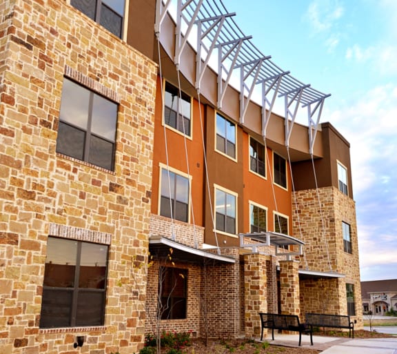 an exterior view of a building with a bench in front of it at Urban Square, Denton, 76210