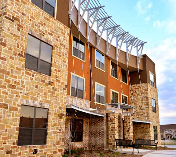 an exterior view of a building with a bench in front of it at Urban Square, Denton, 76210