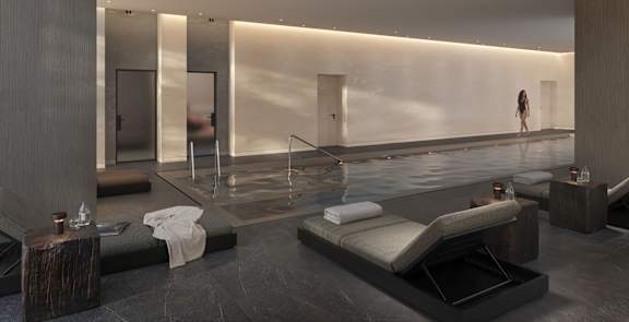 A woman is standing in a modern, minimalist bathroom with a large, rectangular, glass-walled shower.