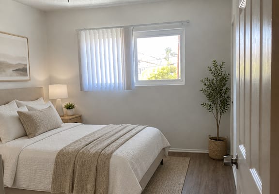 A bedroom with a bed, a ceiling fan, and a window with blinds.