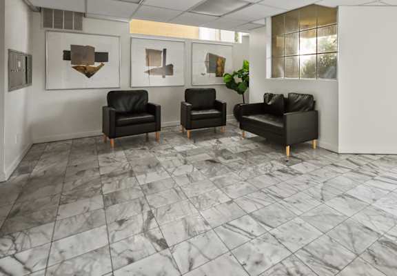 A waiting room with black chairs and a marble floor.