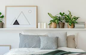 a bedroom with white walls and a white shelf with potted plants on it