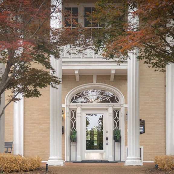 A building with a white arched entrance and a walkway leading to it.