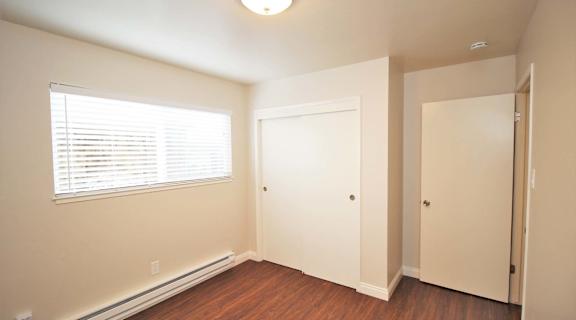 a bedroom with wood flooring and a window and a door