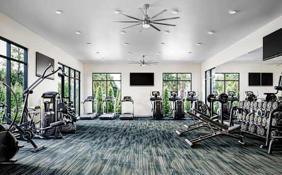 a gym with cardio machines and televisions