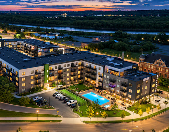 A hotel complex with a pool at night.