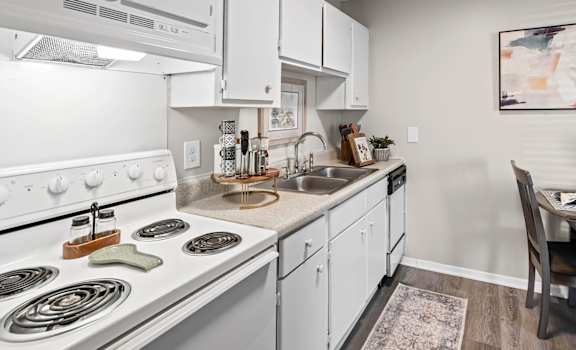 A modern kitchen with white cabinets and a stove top oven.