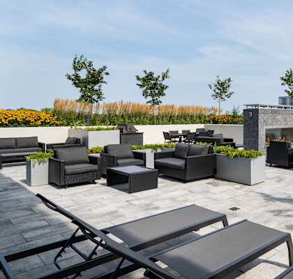 a rooftop patio with tables and chairs and a fire pit