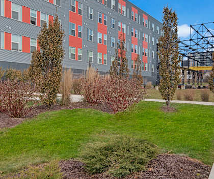 The gray and orange exterior with a metal structure in the background at Stitchweld Apartment Homes. 
