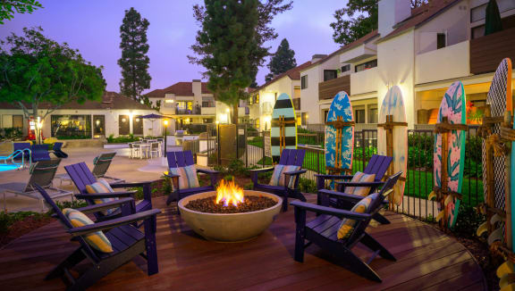 a patio with a fire pit and chairs at night at Sendero Huntington Beach, Huntington Beach
