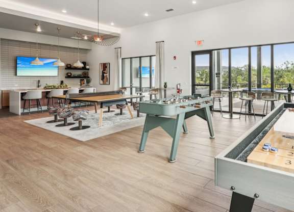 Resident game room with shuffleboard, foosball, and communal seating with TV