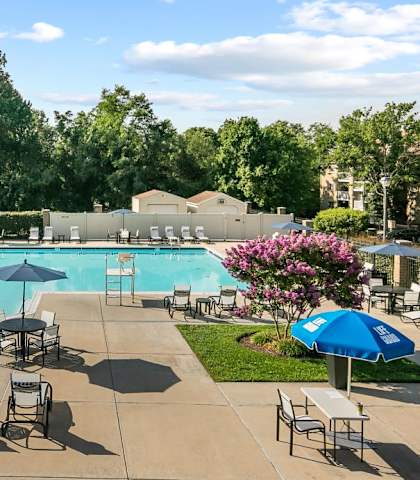 a swimming pool with tables and umbrellas at the resort at McDonogh Township Apartments, Owings Mills, MD, 21117