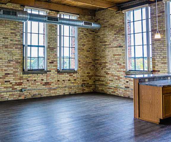 an empty room with a brick wall and large windows