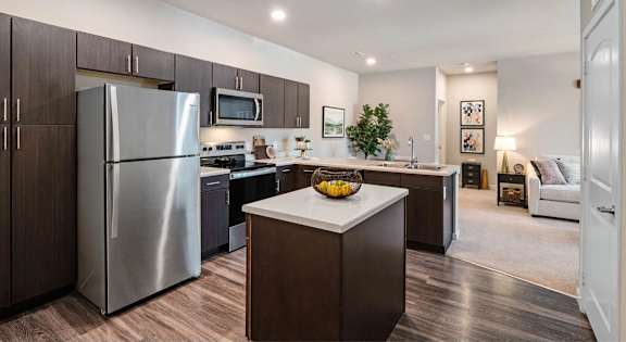 A modern kitchen with a refrigerator, microwave, and oven.