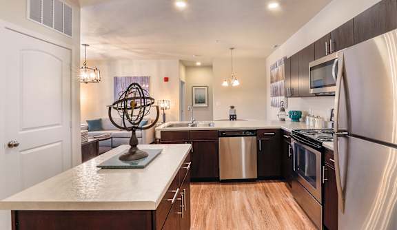 A modern kitchen with a white countertop and stainless steel appliances.