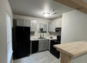 Thumbnail 11 of 27 - a small kitchen with white cabinets and black appliances at The Lodge Apartments, Tulsa, OK