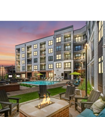 an outdoor patio with a firepit and lounge chairs with a pool in the background