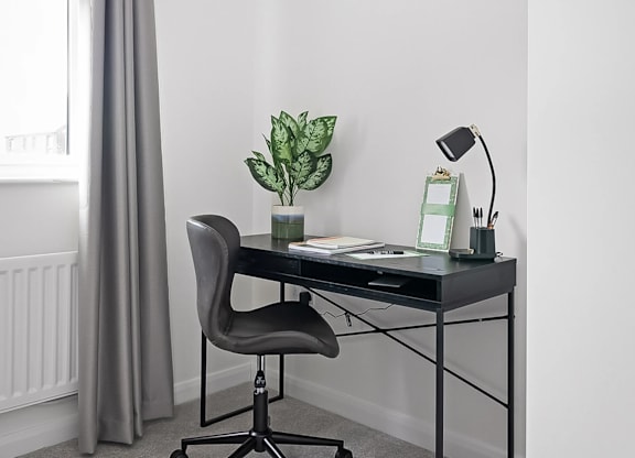 A black desk with a plant and a lamp on it. at The Woodlands Apartments, Milton Keynes
