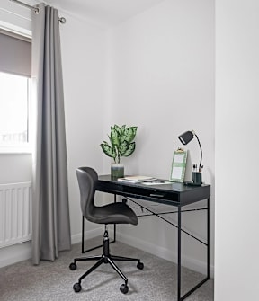 A black desk with a plant and a lamp on it. at The Woodlands Apartments, Milton Keynes