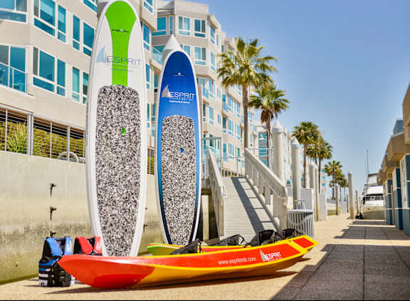 A surfboard with a green and blue design is leaning against a building. at Esprit Apartments, California