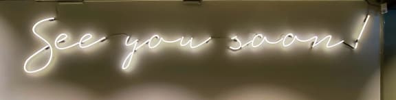 a neon sign that reads see you soon on a wall