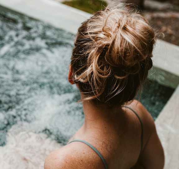 Woman sitting in pool at AVIA Lofts on Parkway Apartments, Vancouver, 98662