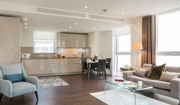a living room with a couch and a table in front of a kitchen