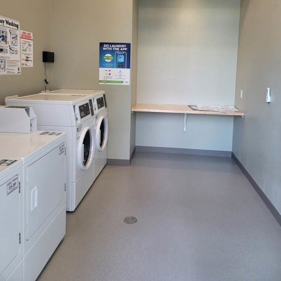 Laundry room at Lavender with two washing machines and dryers and a folding table.