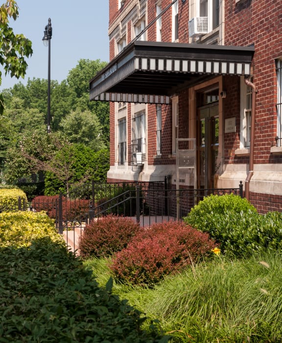 the front of a brick house with a porch and a garden