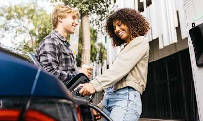 A man and a woman are interacting with a car's touchscreen interface.