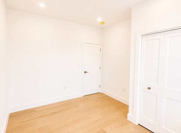 A room with wooden flooring and two white doors.