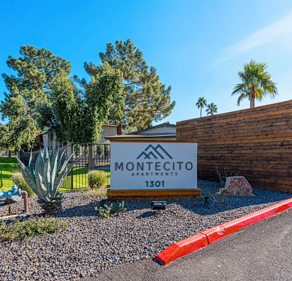 A sign for Montecito Apartments is in front of a building and some trees.